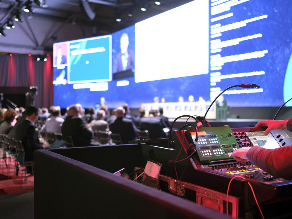 Technician handling stage lights and sound at a conference.